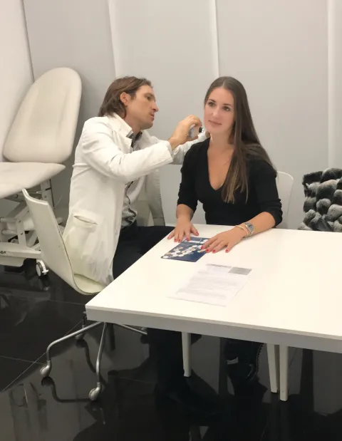 Zdravnik pregleduje kožo pacientke z dermatoskopom